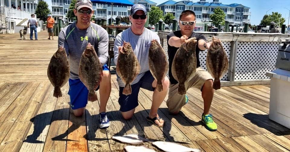 Anglers holding flounder on dock after shore fishing trip