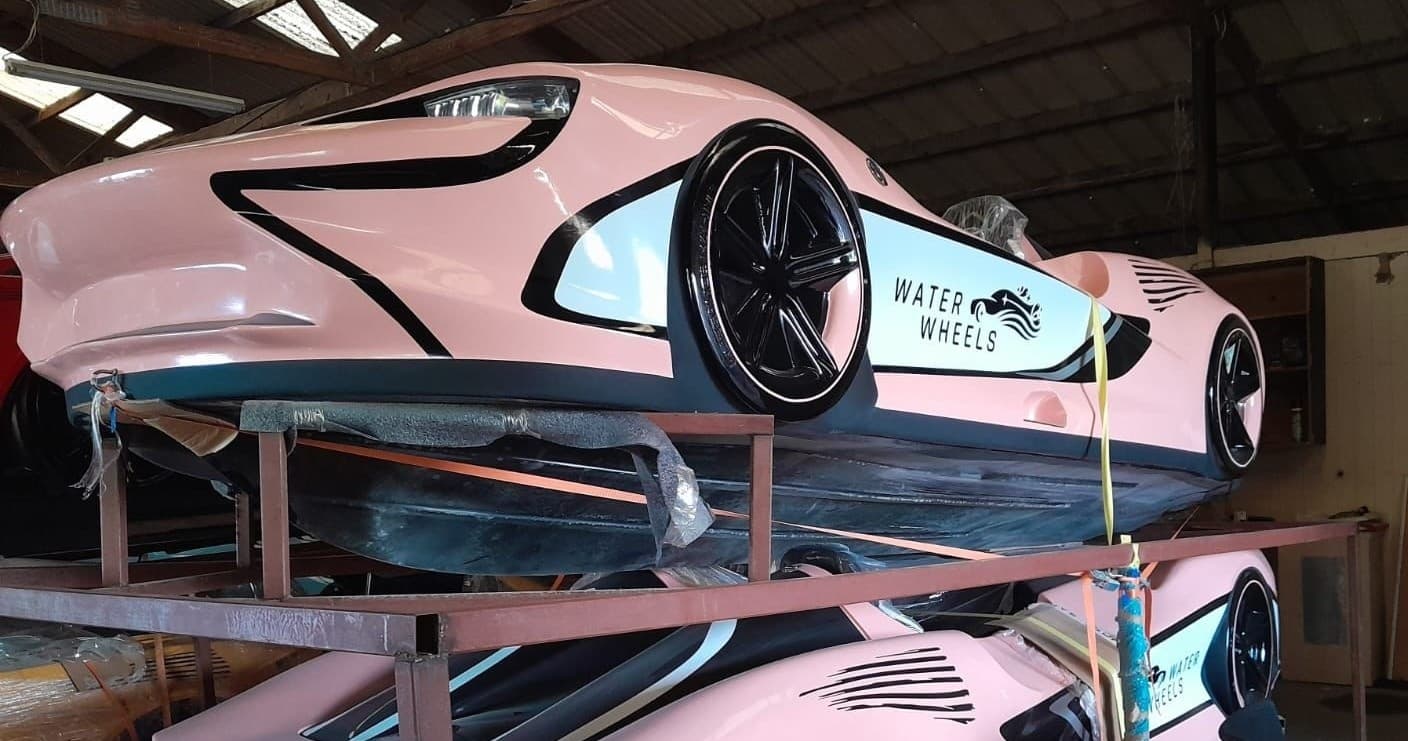 Stacked pink amphibious car hulls stored indoors in warehouse storage