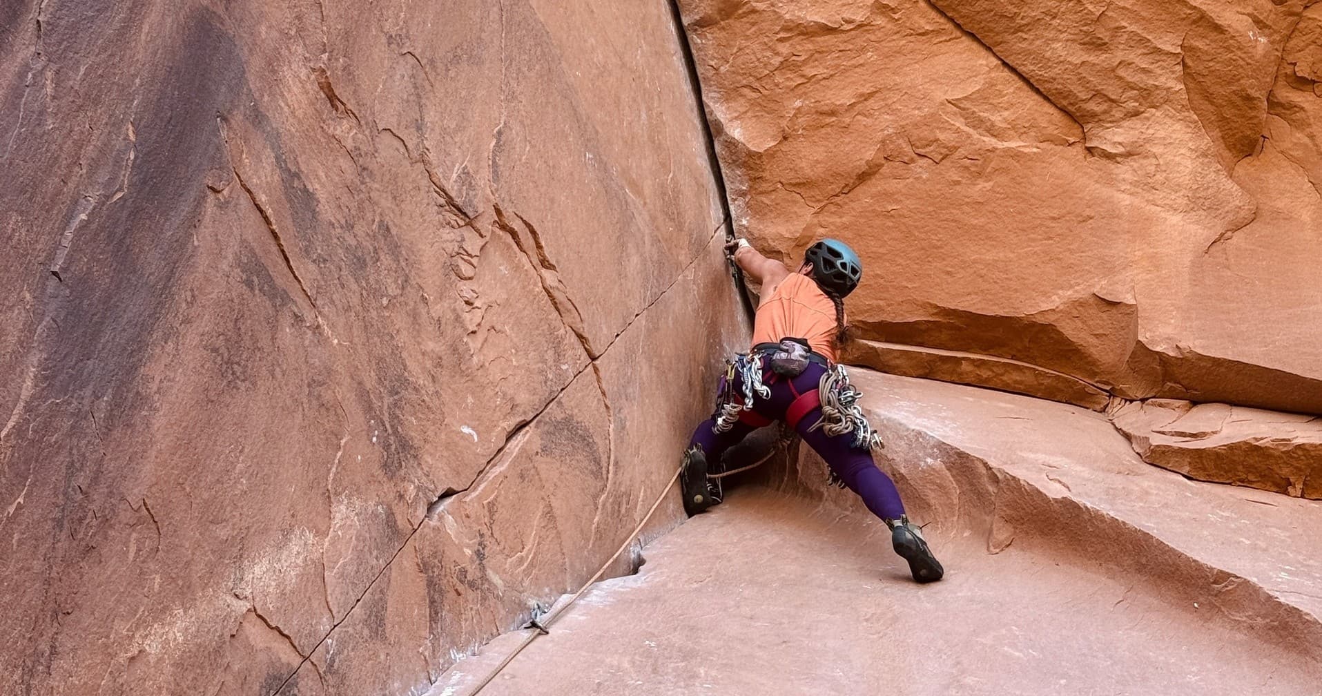 Climber stemming across a sandstone crack in desert canyons
