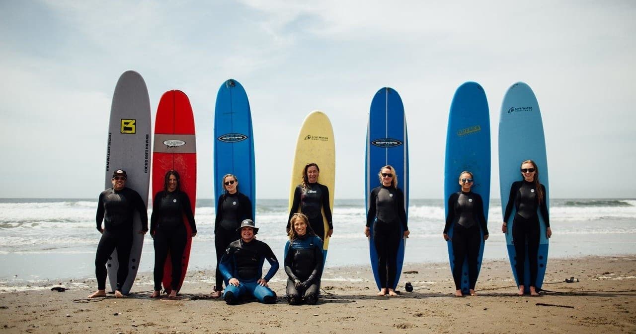 Surfers and longboards lined on foggy beach before surf session