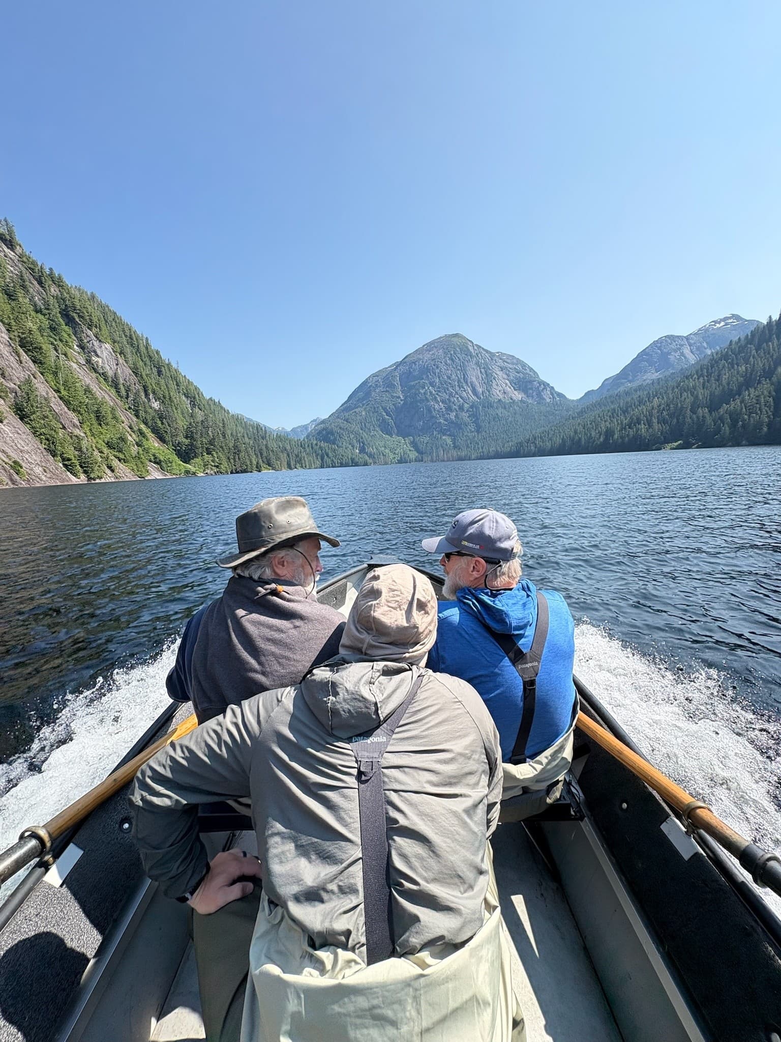 Guides in boat crossing alpine lake, remote fishing expedition underway