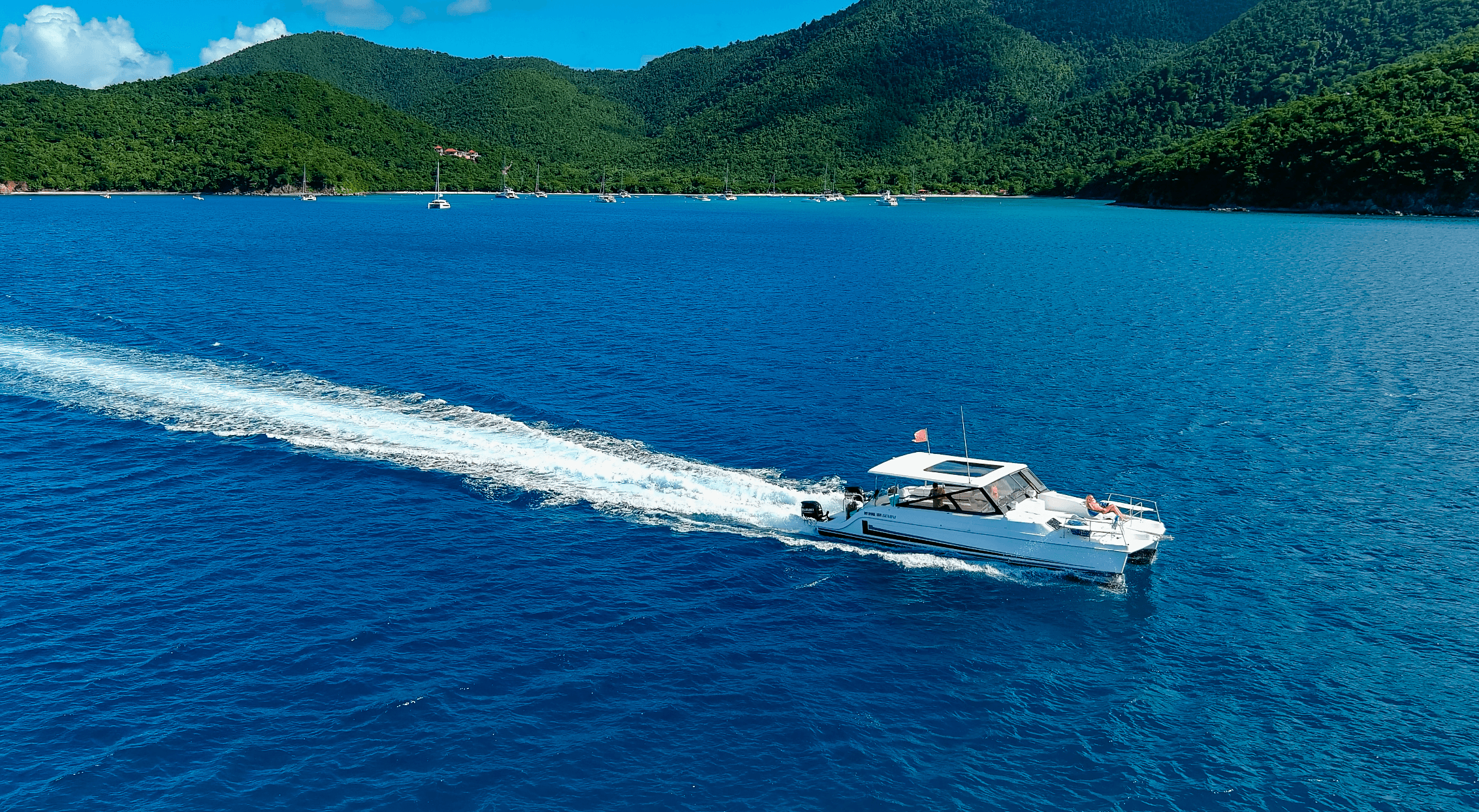 Powerboat cutting through turquoise Caribbean waters near island