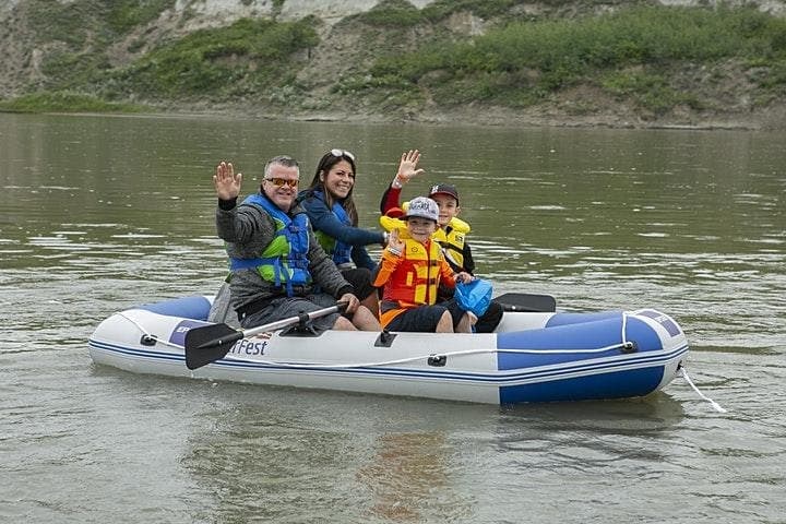 Family rafting on river in lifejackets amid green canyon