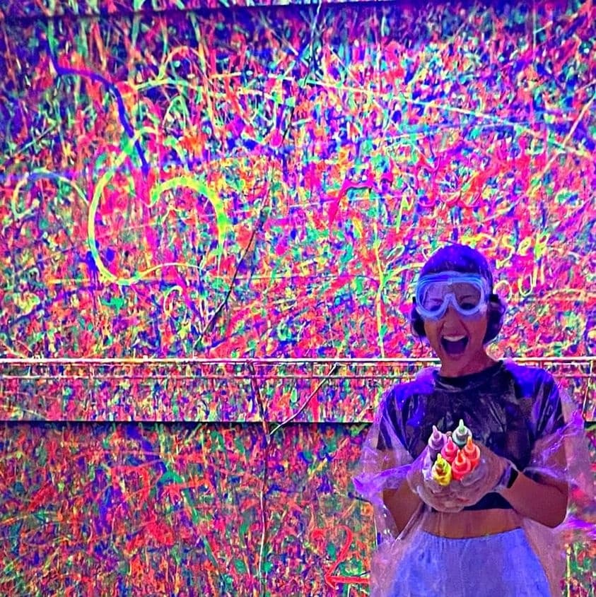 Person covered in neon paint during colorful splatter art event