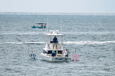 Offshore sportfishing boat trolling in open ocean, anglers aboard