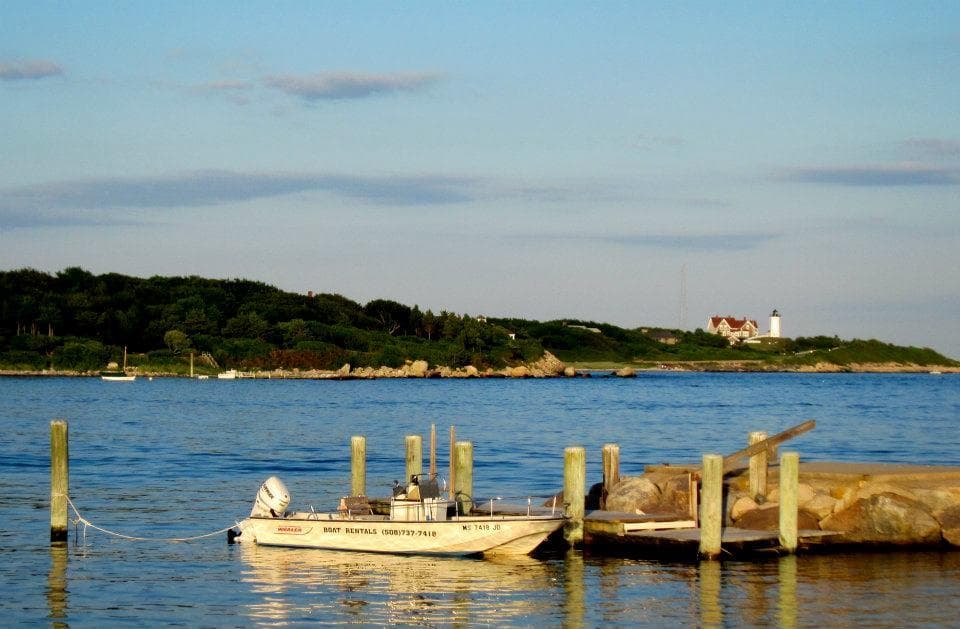 Scenic coastal pier and distant lighthouse over calm bay for boating