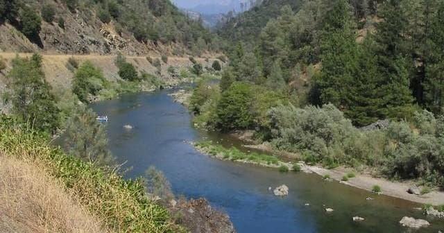 Scenic river valley with calm flow and distant forested mountains