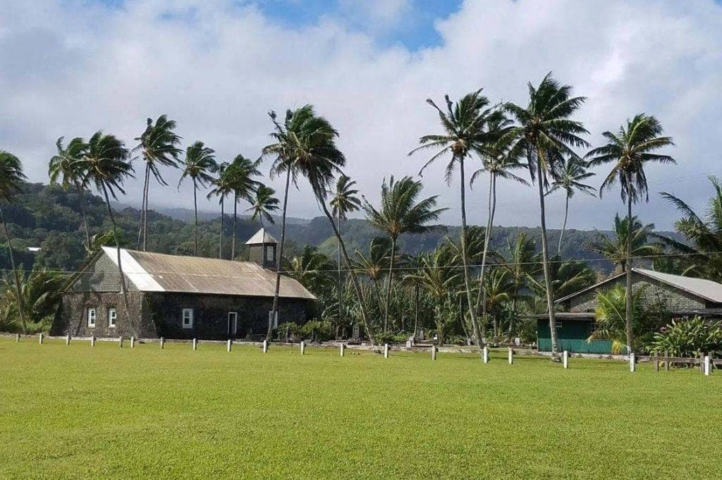 Historic coastal church by palm grove and open green field