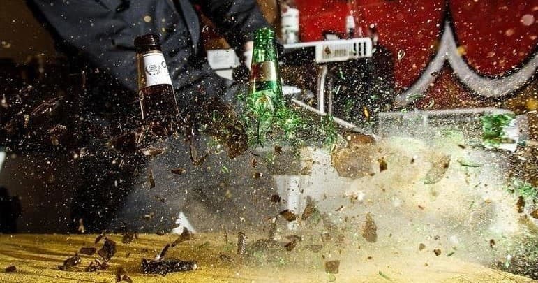 Bottles exploding against wall in indoor smash room action, Tucson