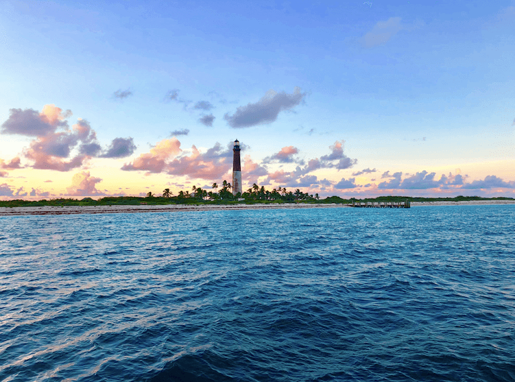 Coastal lighthouse at sunset over calm ocean for boat tours
