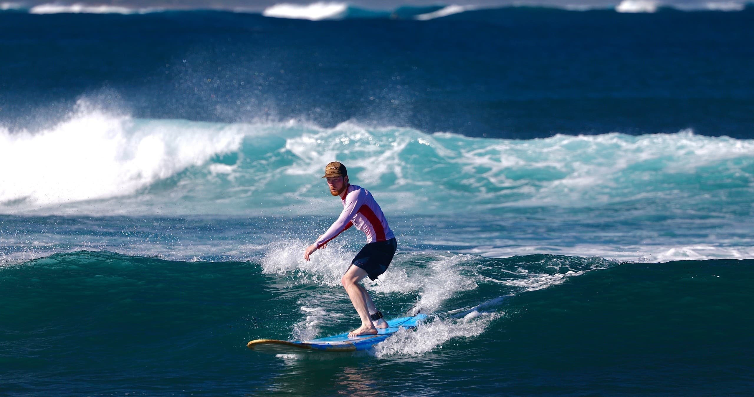 Surfer carving a blue ocean wave at coastal beachbreak