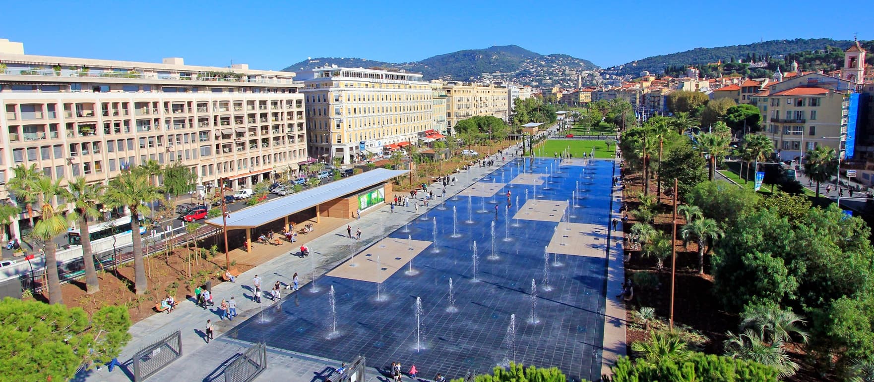 Sunny urban waterfront promenade with interactive fountains on Nice seafront