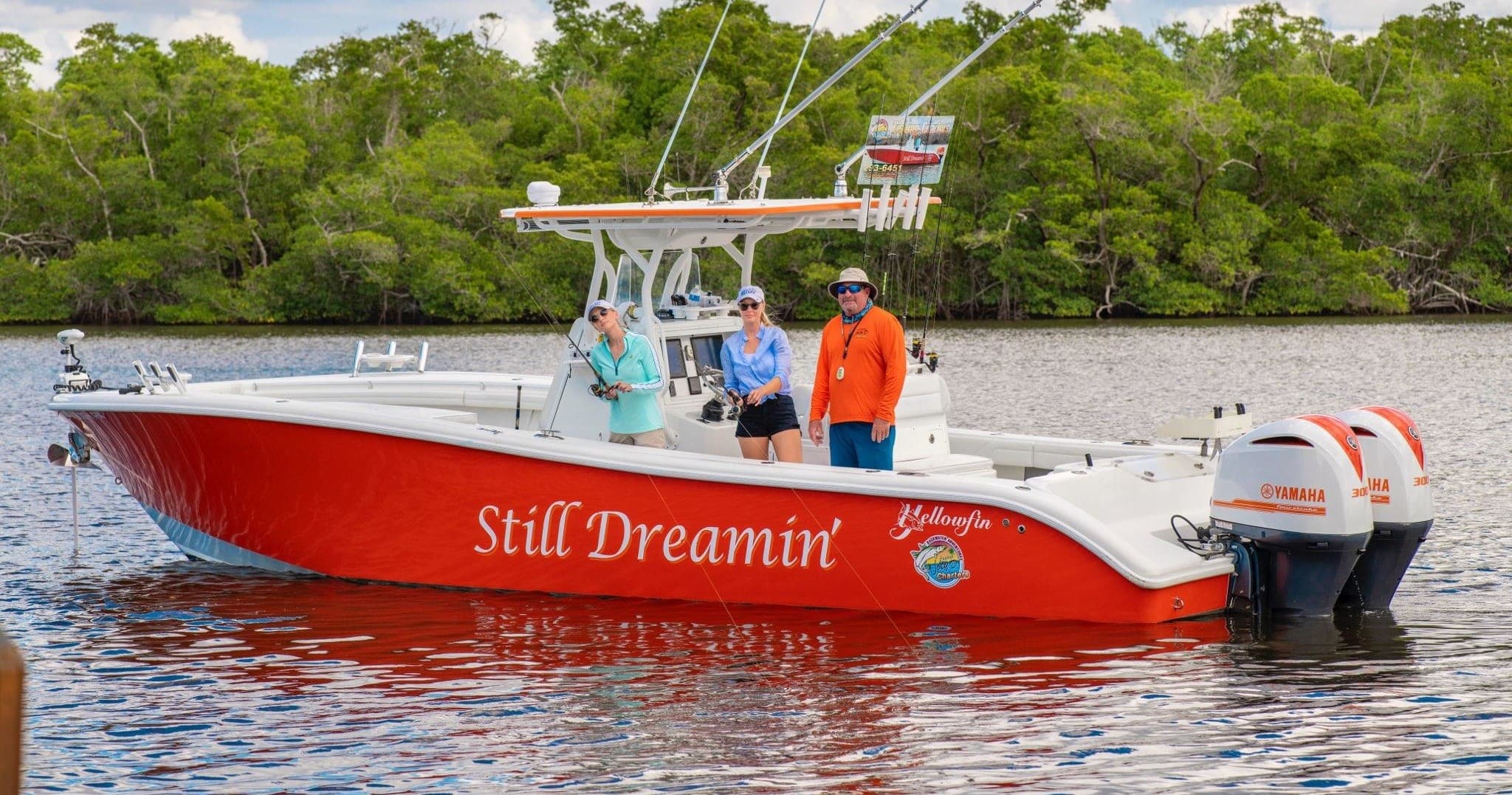 Red sportfishing boat cruising mangrove-lined coastal waters