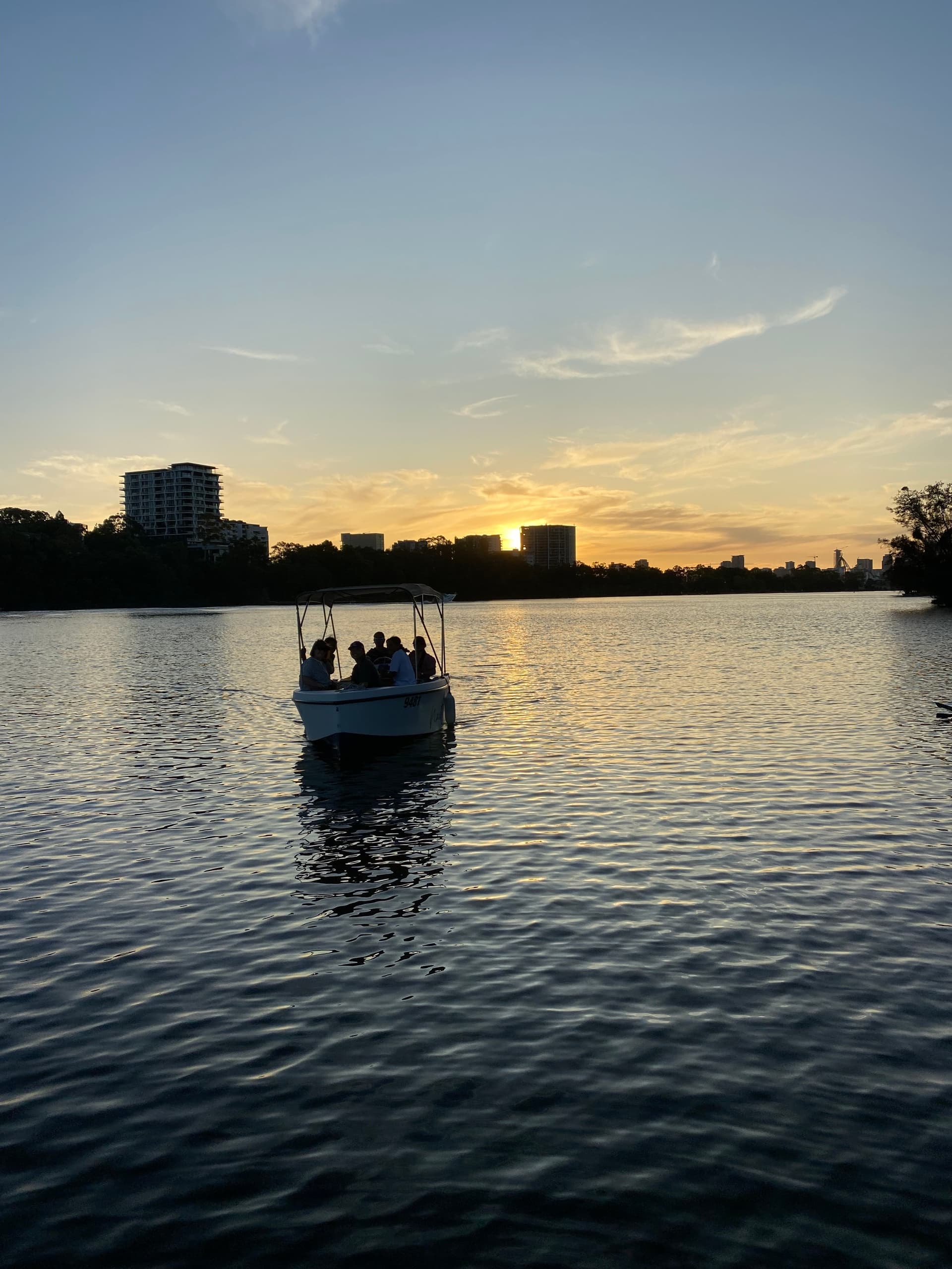 Sunset boat silhouette cruising across calm lake at dusk