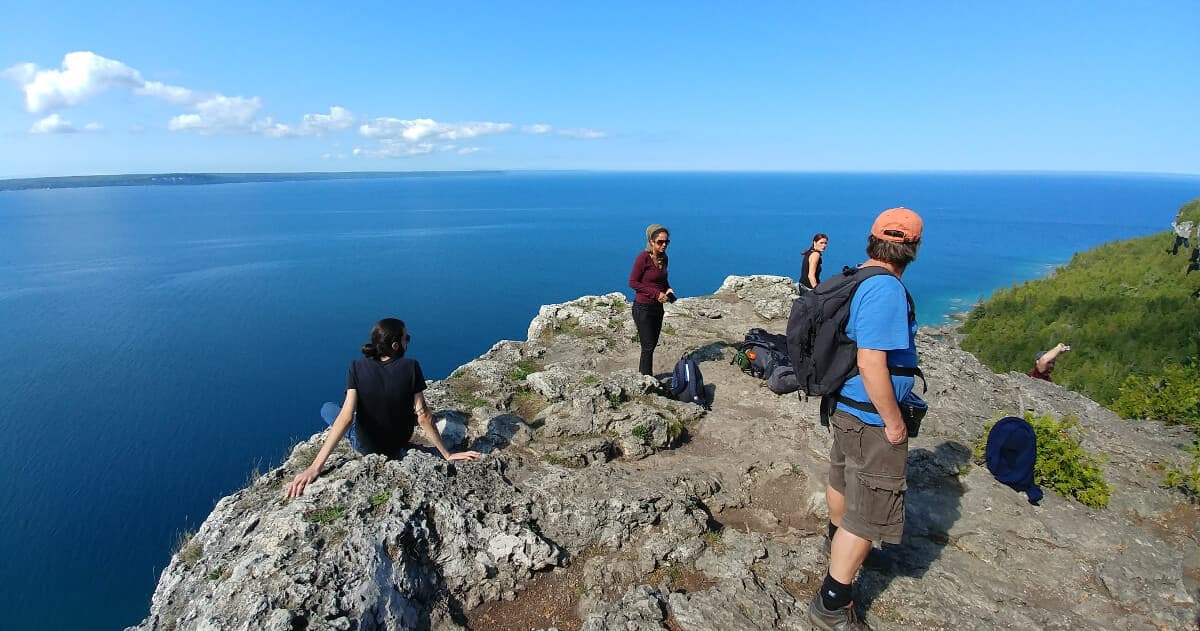 Hikers on coastal cliff overlooking blue ocean and horizon