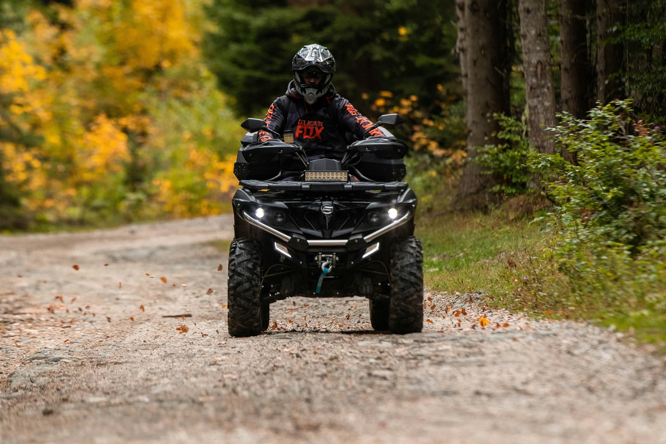 ATV rider splashing through muddy trail surrounded by wild countryside