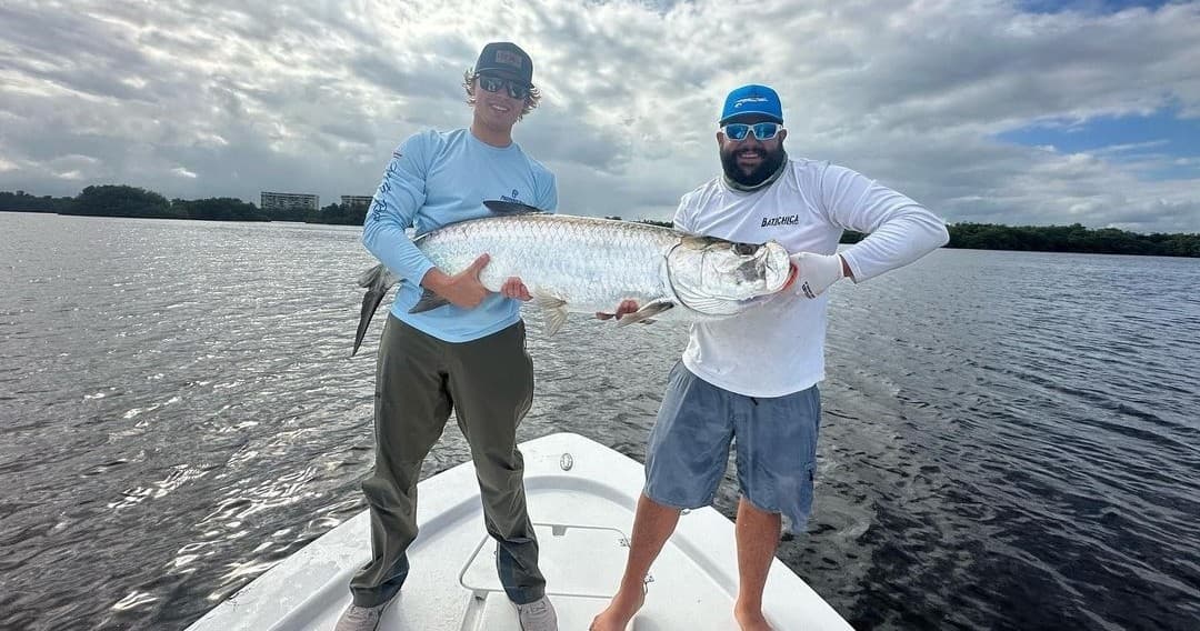 Anglers holding large tarpon on bow during inshore fishing trip