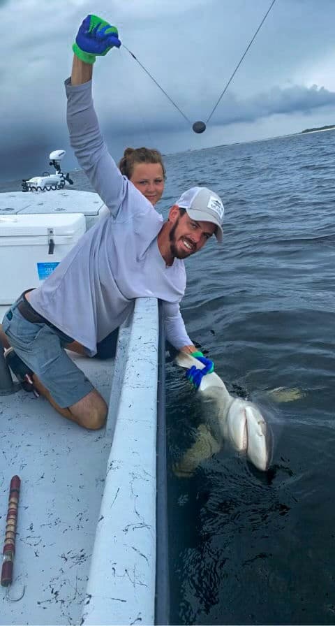 Angler landing large fish from coastal charter boat at sea