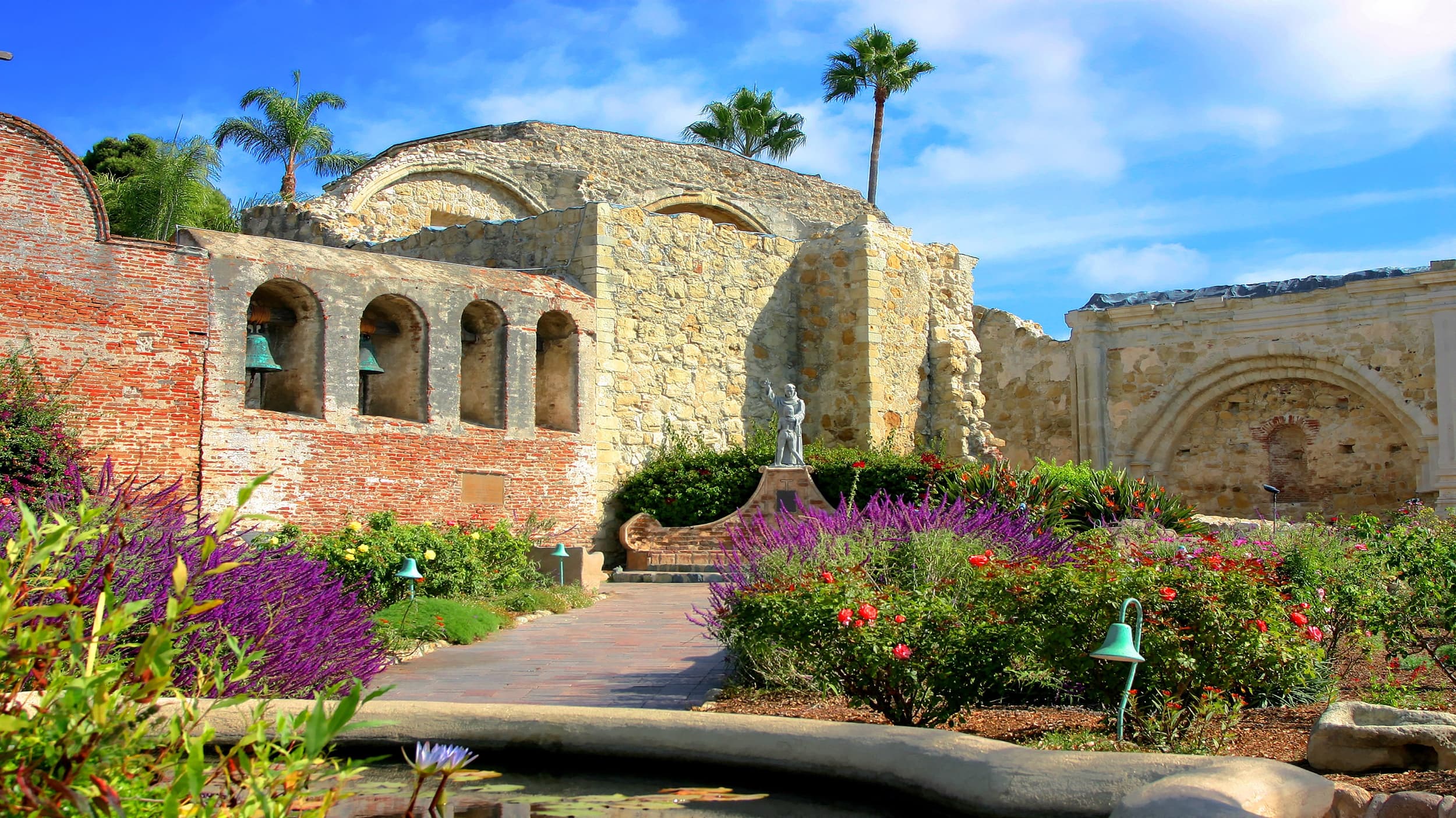 Historic seaside ruins and garden pathways under blue sky