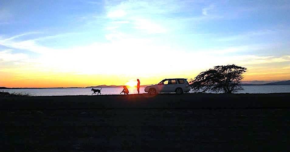 Sunset beach silhouettes with parked vehicle and people