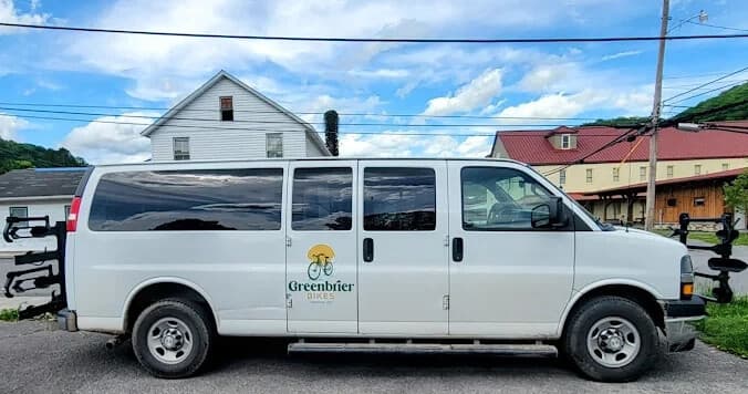 Greenbrier bike shuttle van parked by rural roadside under blue sky