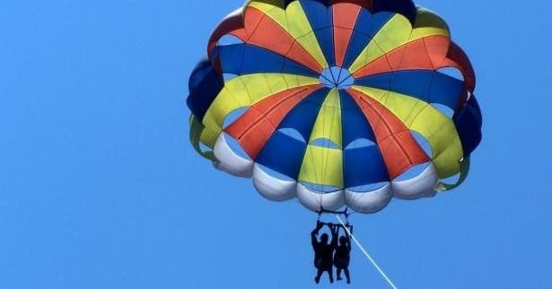 Parasailers under colorful canopy over clear Gulf Coast waters