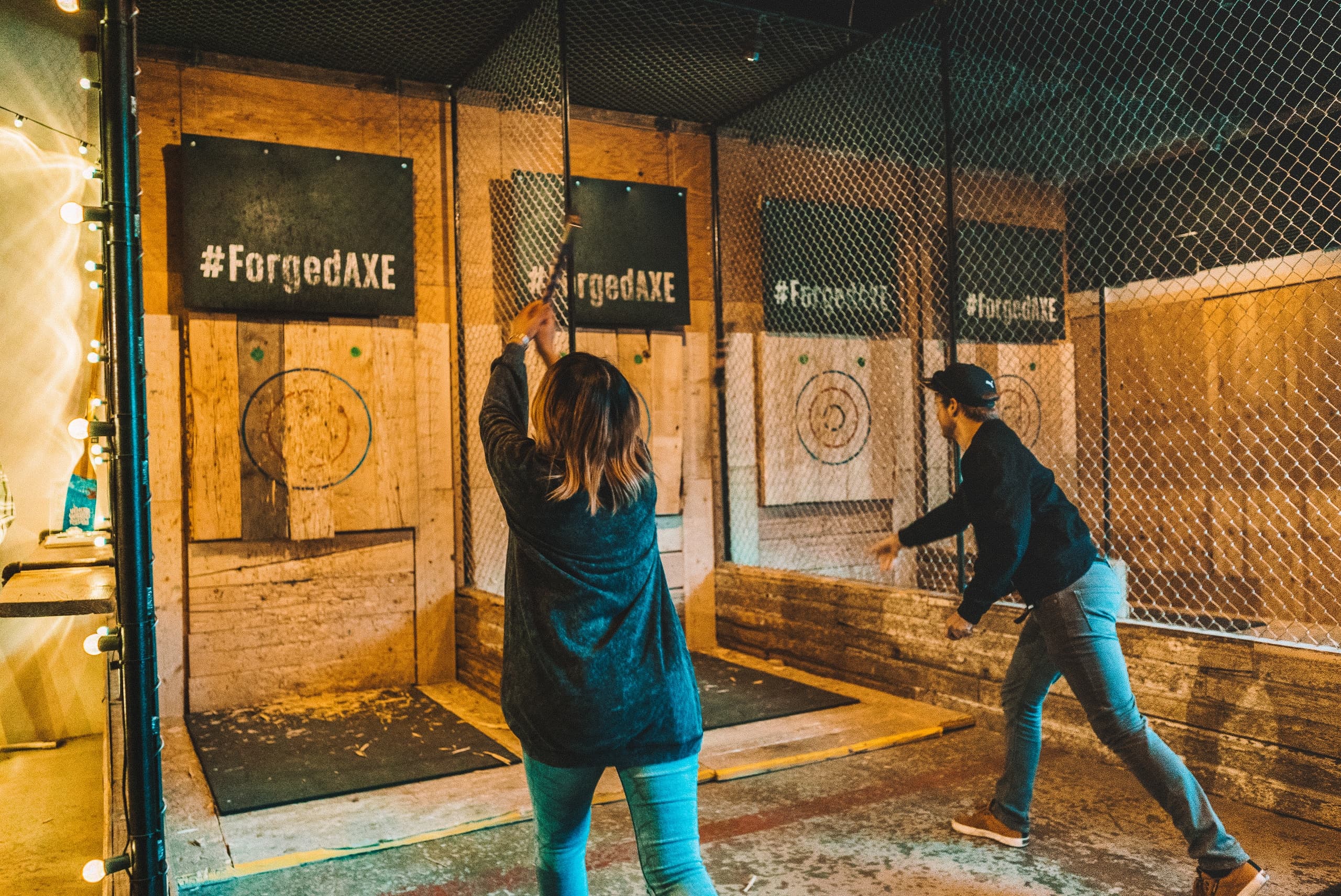 Two people axe throwing in lanes at indoor target range