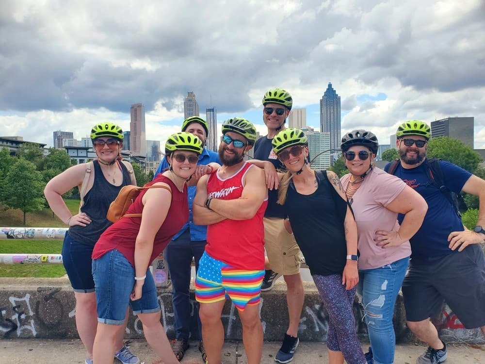 Smaller bike tour crew smiling with downtown Atlanta skyline
