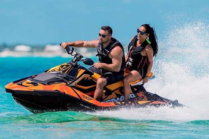 Two people jet skiing on turquoise ocean waters near coast
