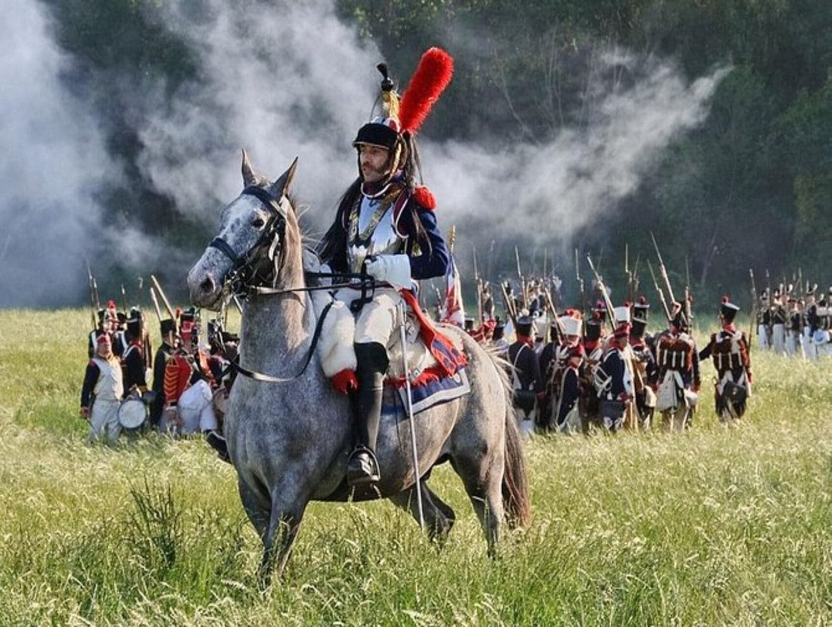Mounted cavalry reenactors charging across grassy field outdoors