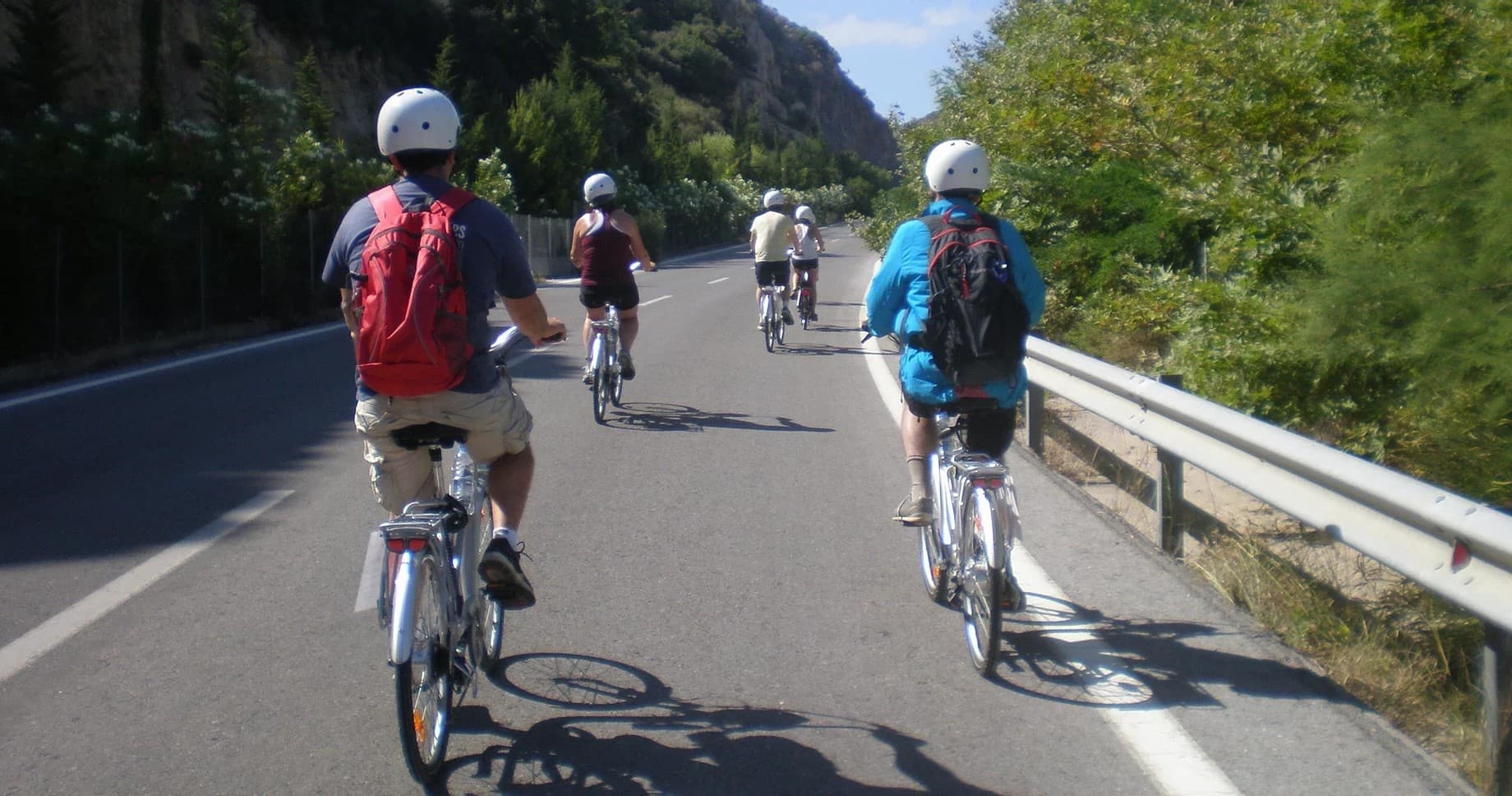 Group cyclists riding along coastal road in sunny Crete