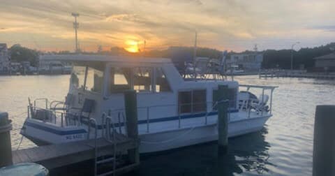 Docked charter boat at harbor during golden sunset on calm bay waters