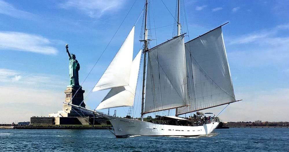Sailboat cruising near Statue of Liberty on calm New York Harbor waters
