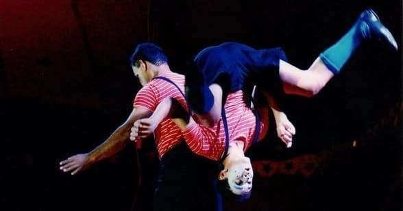 Acrobats performing aerial flip during indoor circus stage show