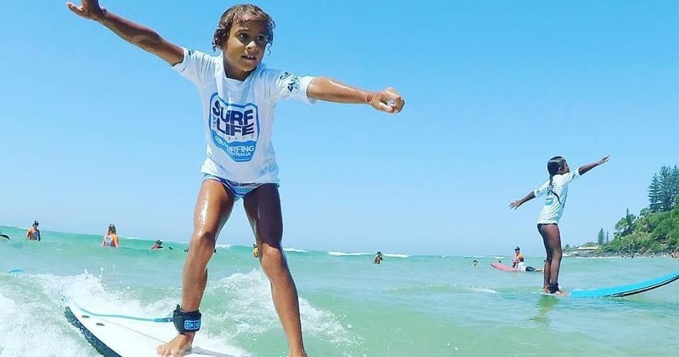 Child surfing small wave at sunny beach surf lesson in Australia