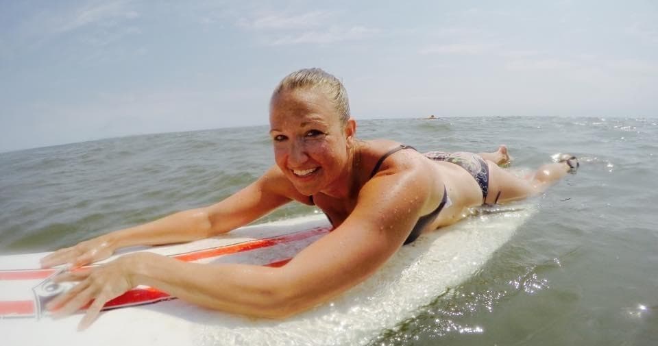 Woman prone on surfboard paddling in calm coastal waters