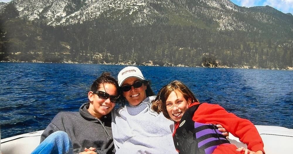 Friends smiling on a boat with Tahoe mountains behind them