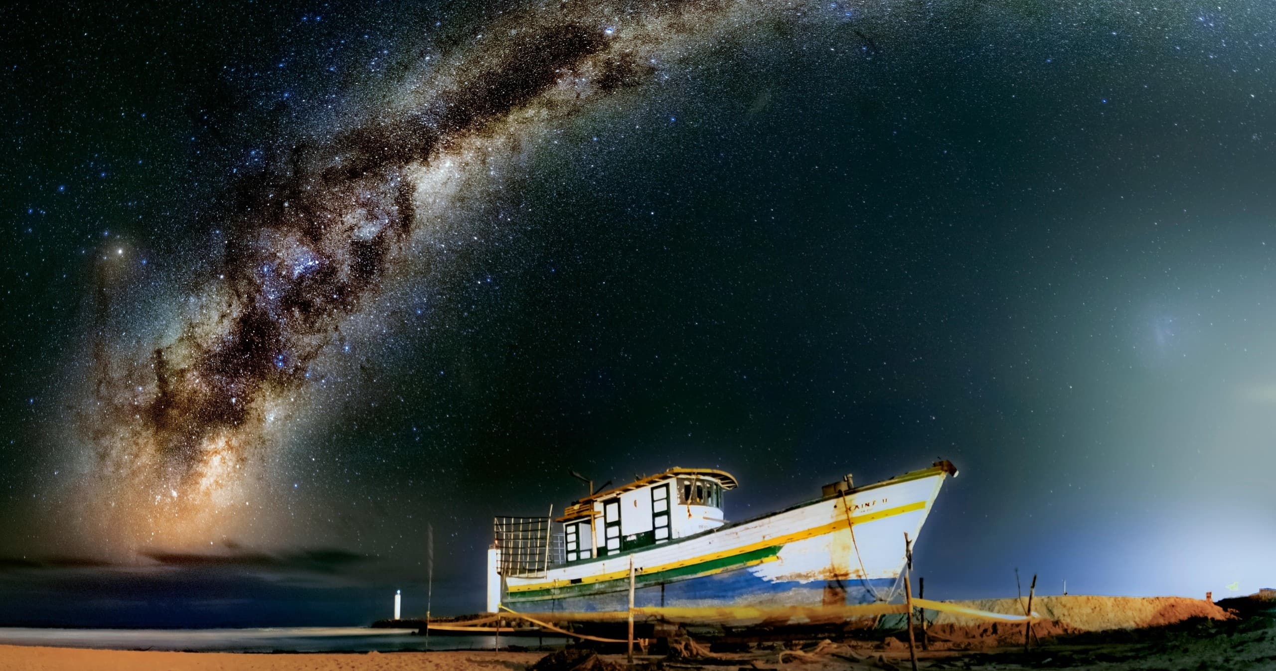 Beached boat under Milky Way on coastal shore for night stargazing