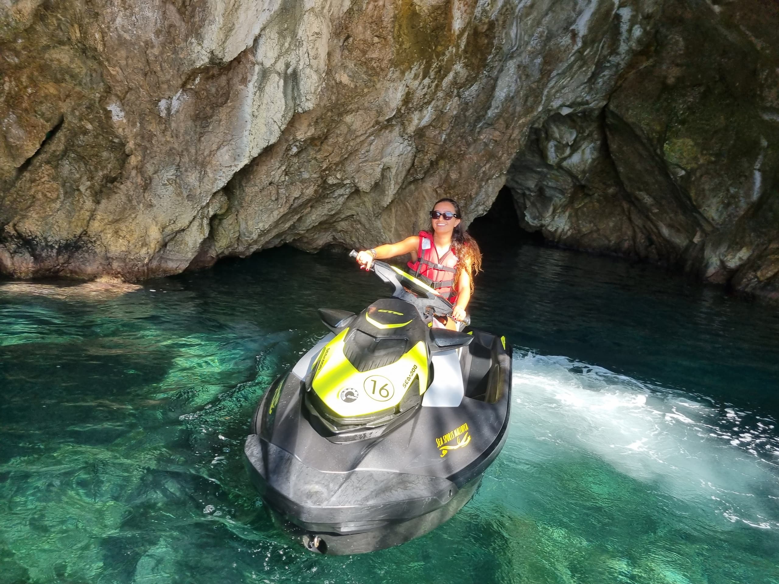 Jet ski riding into sea cave with crystal clear turquoise water