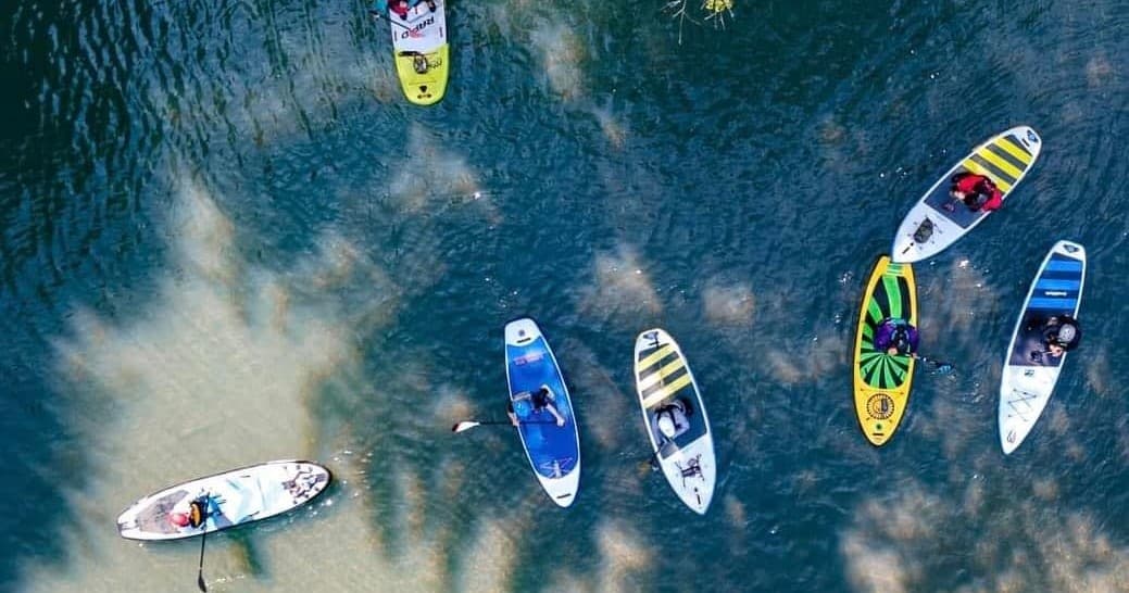 Aerial paddleboard group floating on clear river water