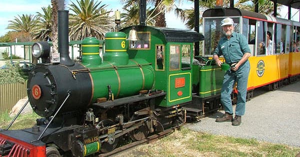 Heritage steam train at coastal park with engineer boarding