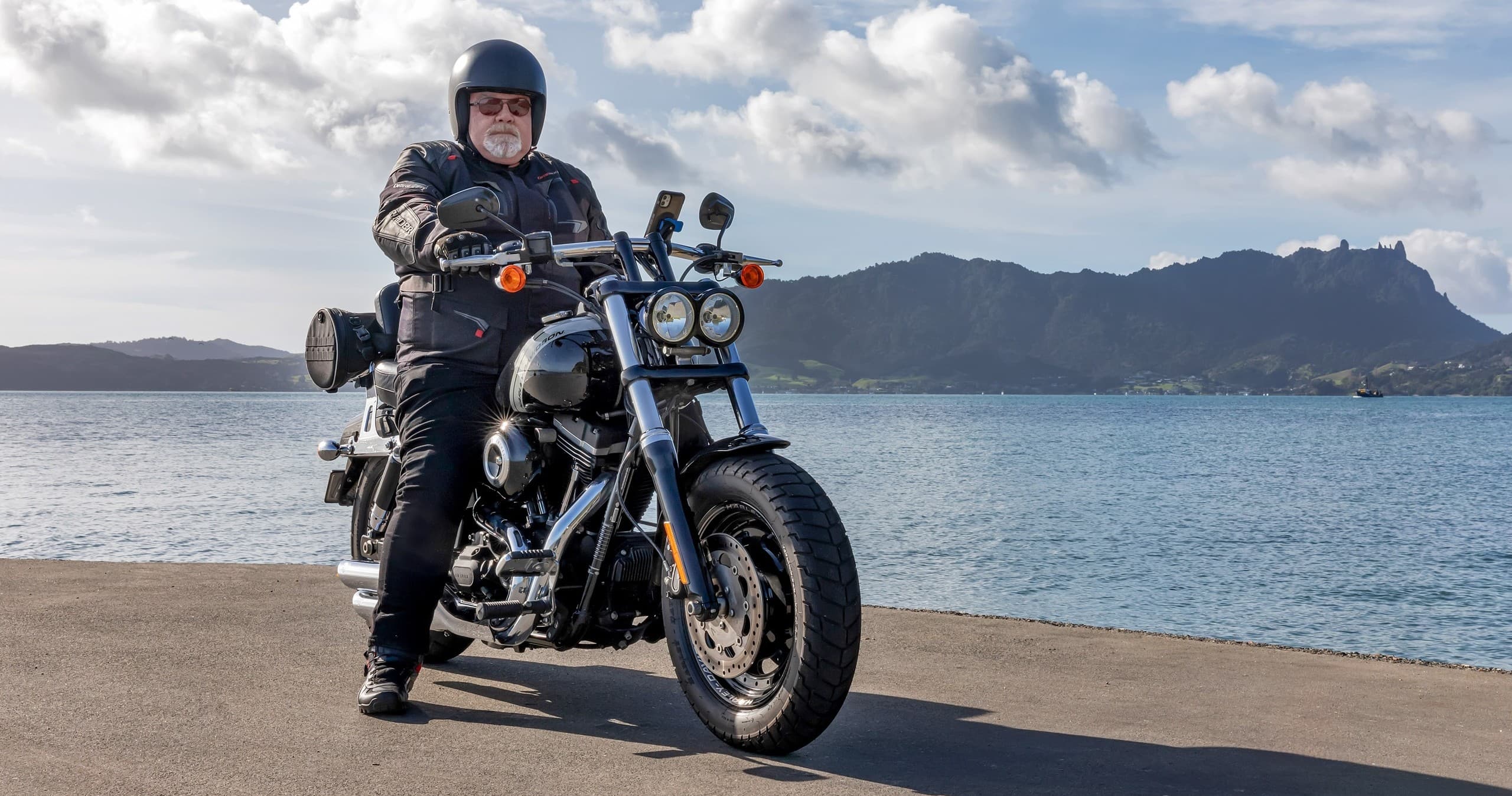 Rider on cruiser motorcycle posed at coastal lookout with water