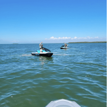 People riding jet skis on clear coastal waters, watersports fun