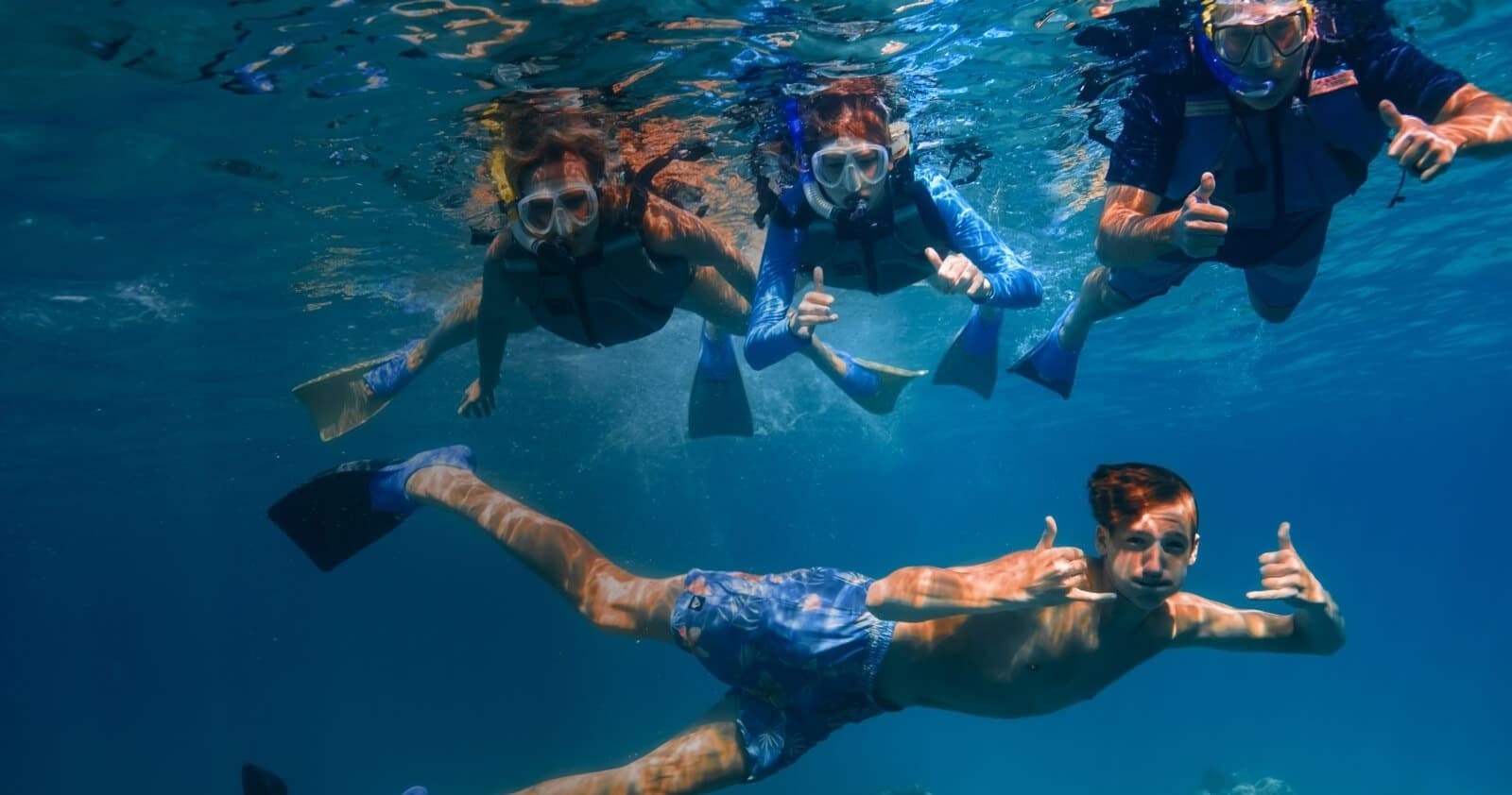 Underwater snorkel group posing near coral off Lanai coast