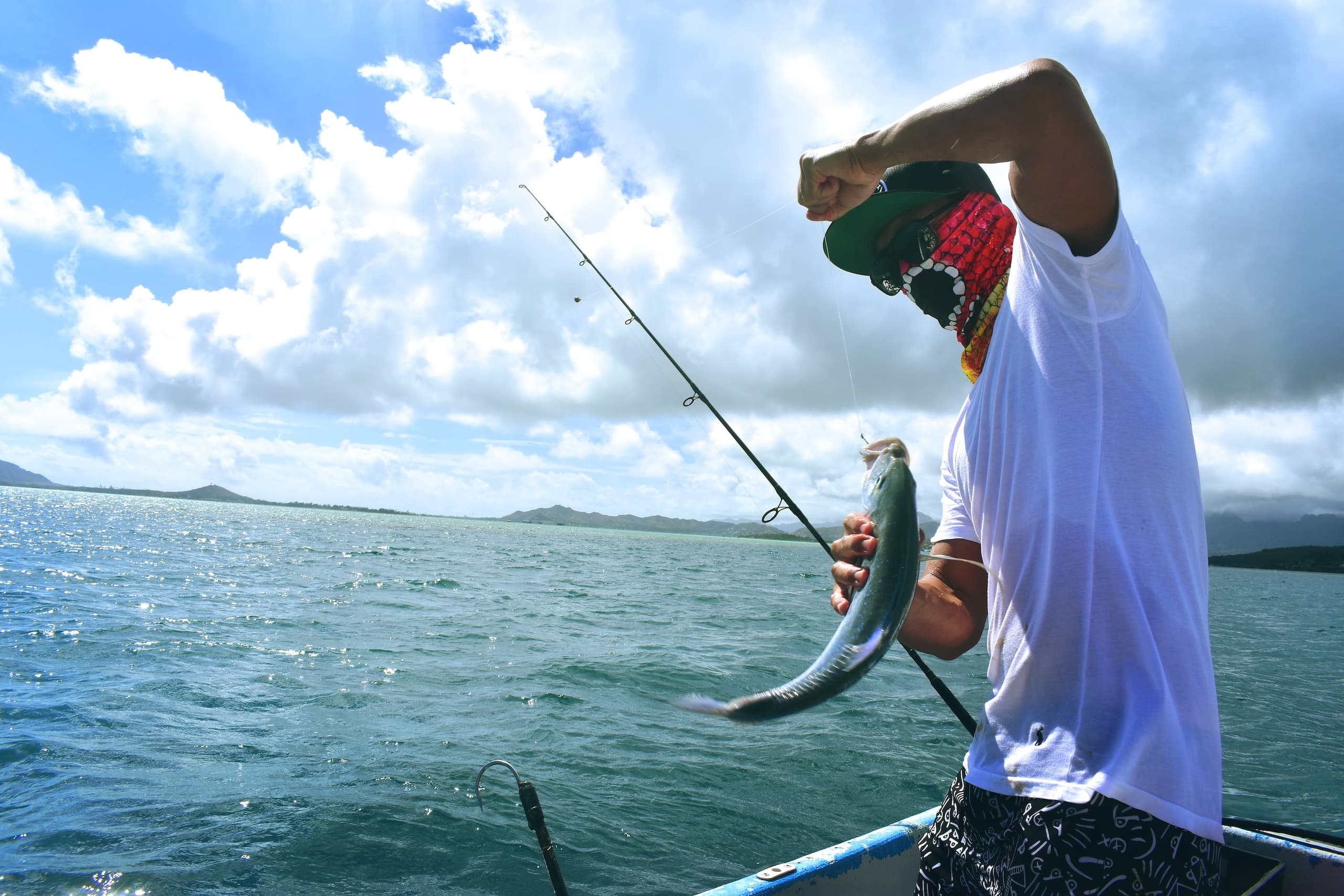 Angler reeling caught fish on charter boat in open sea