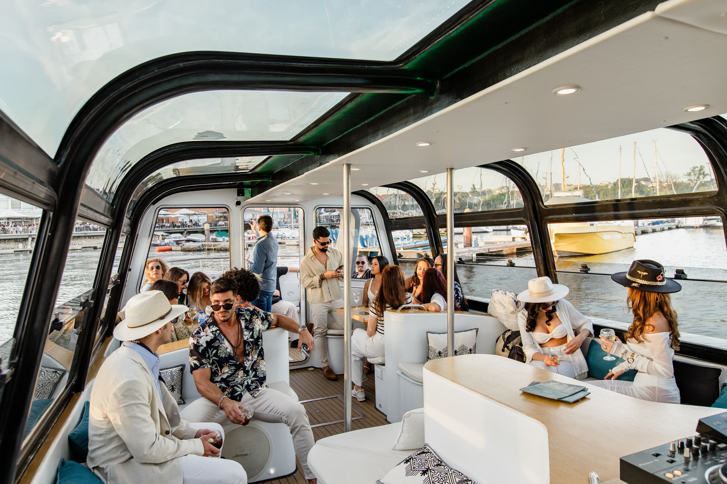 Luxury glass-roof boat lounge with guests cruising marina