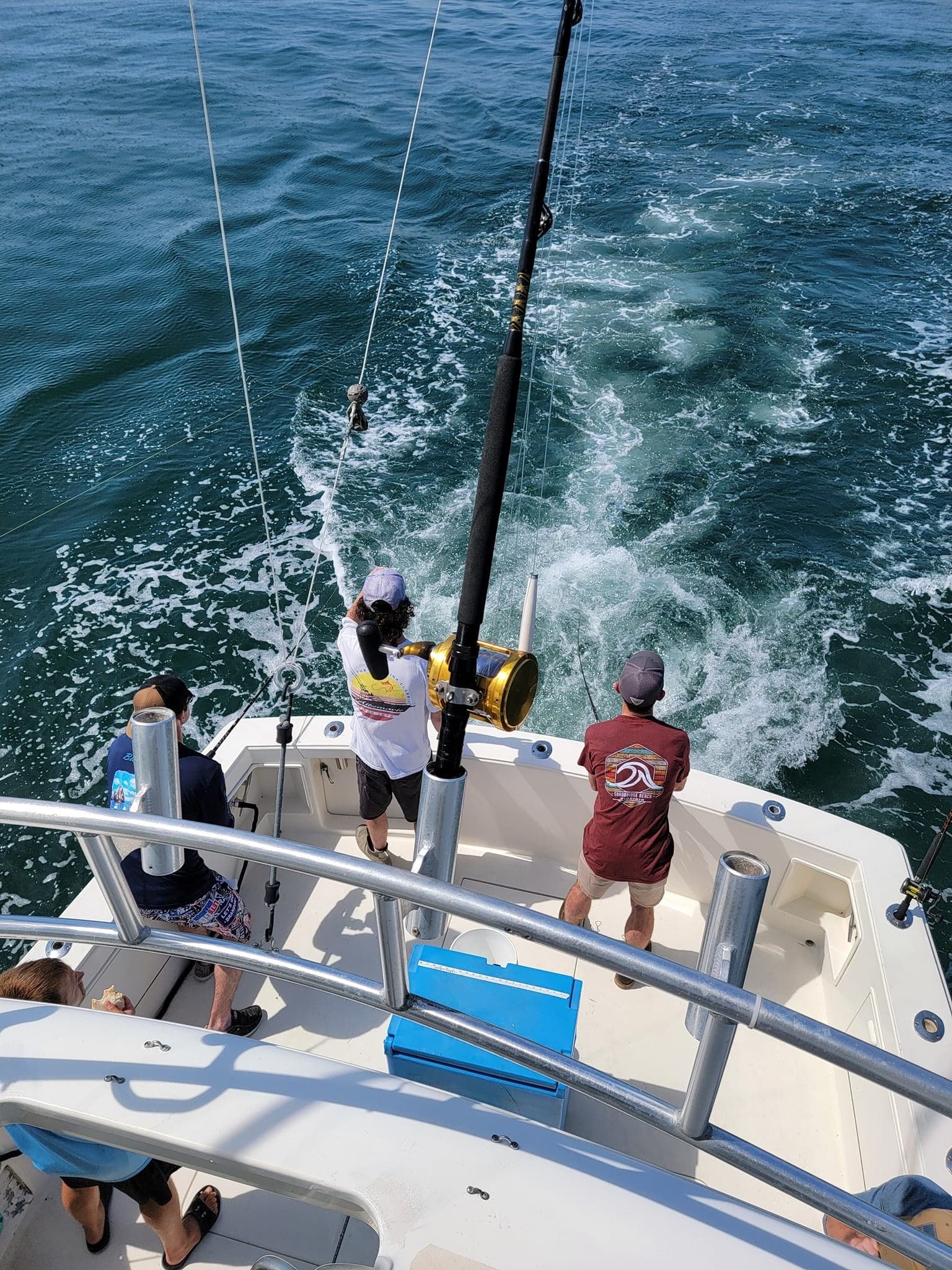 Sportfishing crew hauling big game fish from boat on ocean