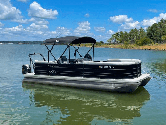 Black pontoon boat gliding on emerald lake under blue skies