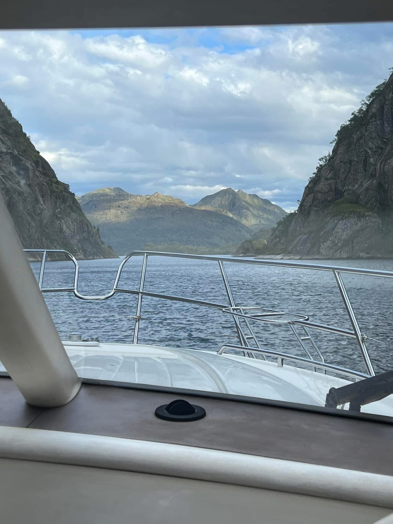 Boat bow entering dramatic Norwegian fjord between cliffs