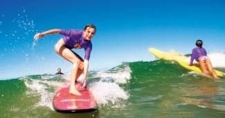 Surfer carving a wave on a pink board at sunny beach